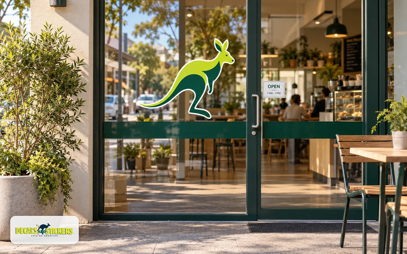 Café glass doors with a large kangaroo logo decal, a small opening hours sticker and a dark green safety band across the glass at waist height